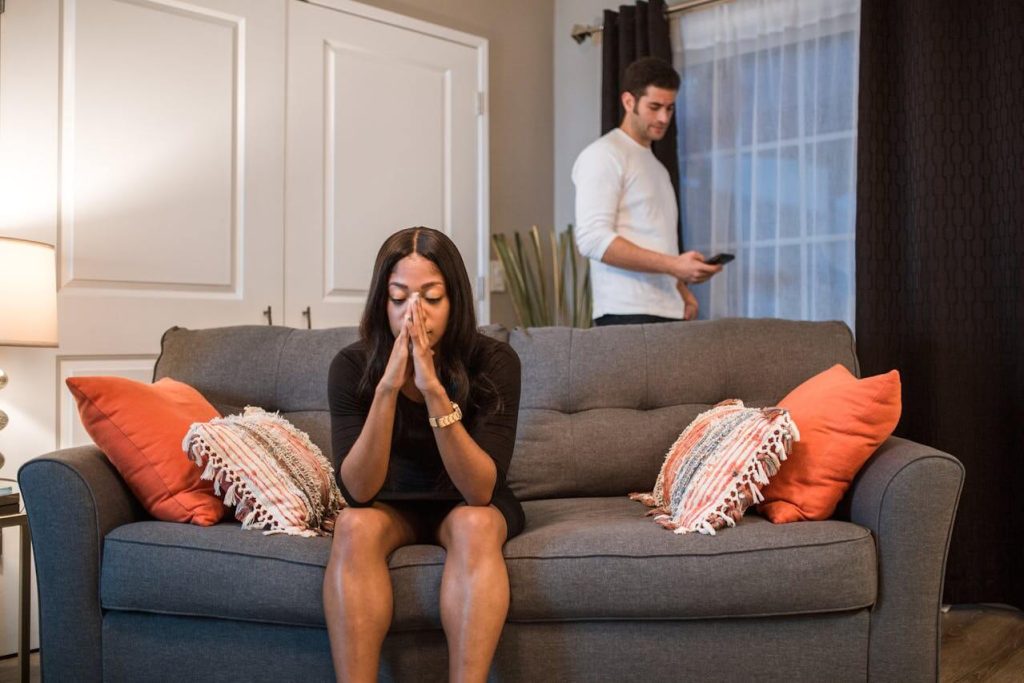 A woman sitting on the sofa while a man is standing at the back